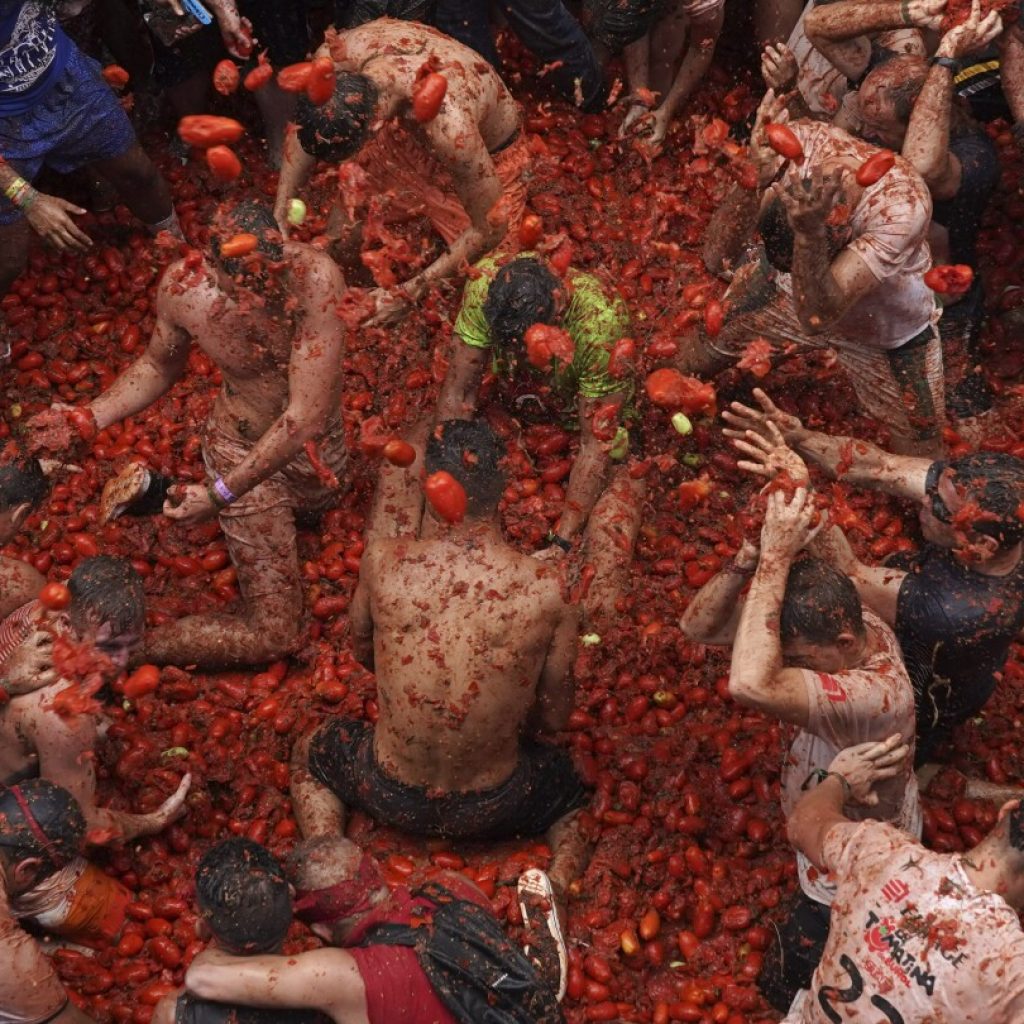 Revelers hurl tomatoes at each other and streets awash in red pulp in Spanish town’s Tomatina party | AP News