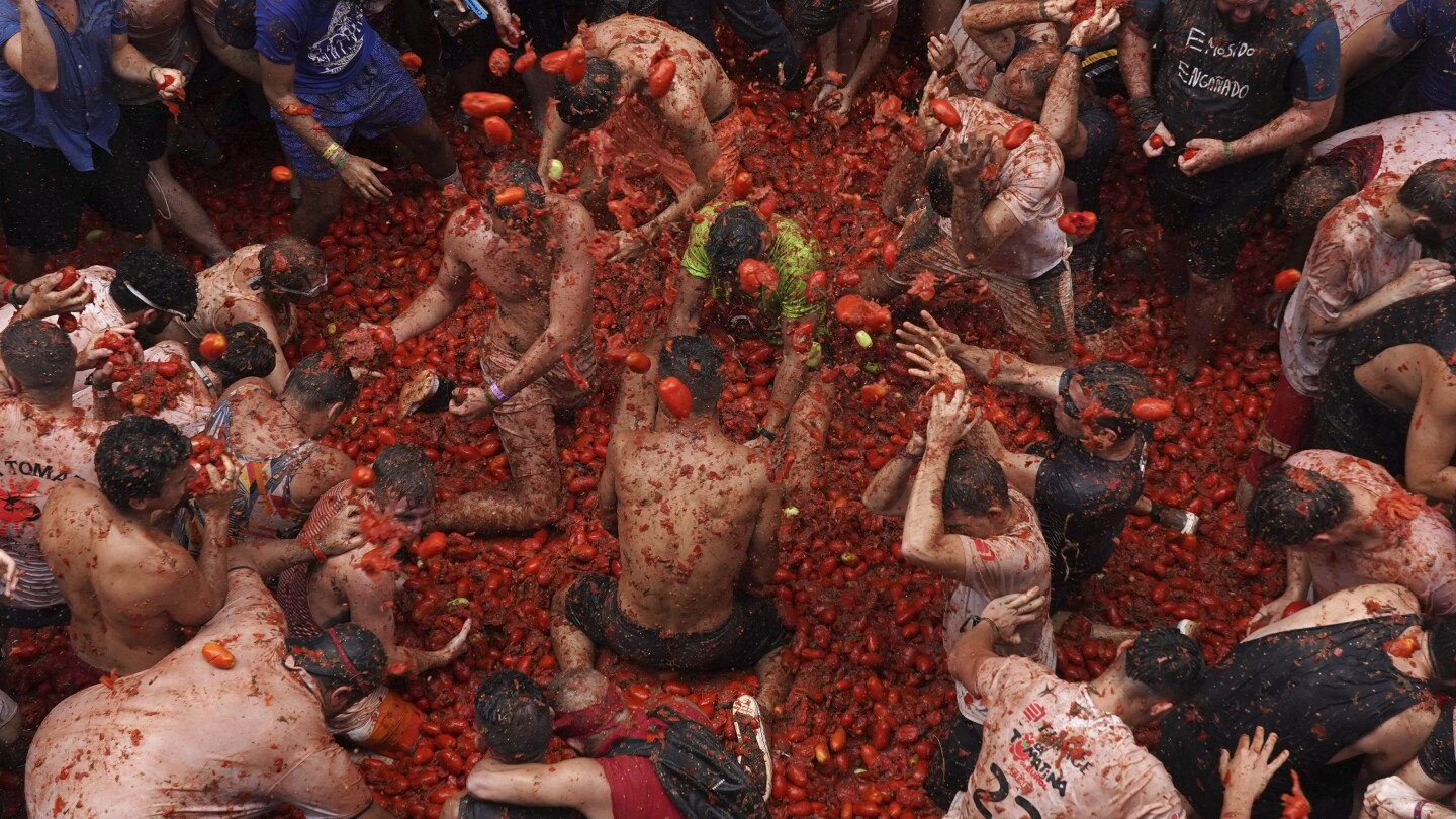 Revelers hurl tomatoes at each other and streets awash in red pulp in Spanish town’s Tomatina party | AP News
