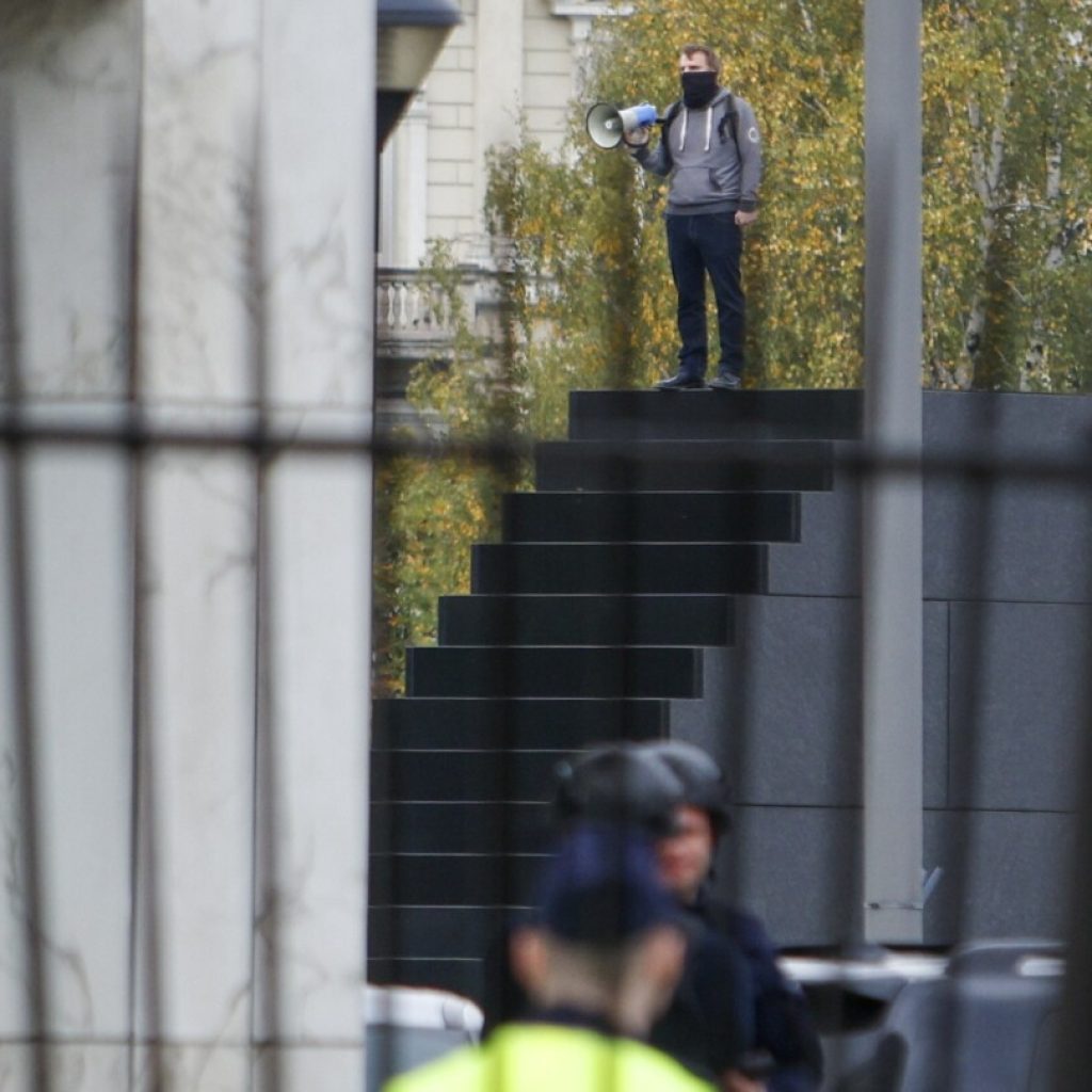 Police in Warsaw detain a man who climbed a monument and reportedly made threats | AP News