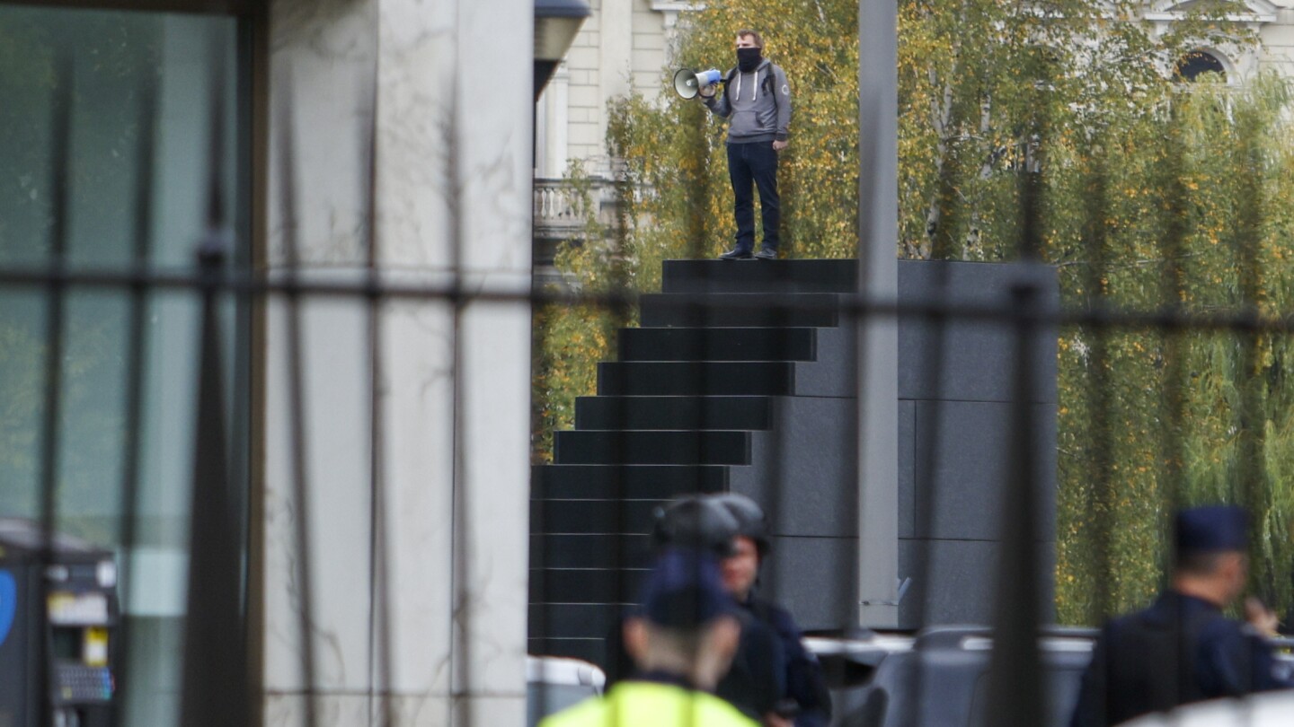 Police in Warsaw detain a man who climbed a monument and reportedly made threats | AP News