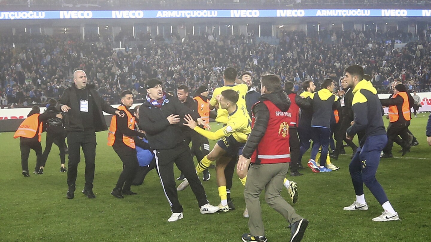 Trabzonspor fans invade pitch, attack Fenerbahce players in Turkey. Police have detained 12 people