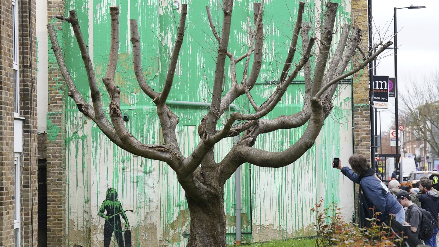 A new Banksy mural sprouts beside a cropped tree in London. Many see an environmental message