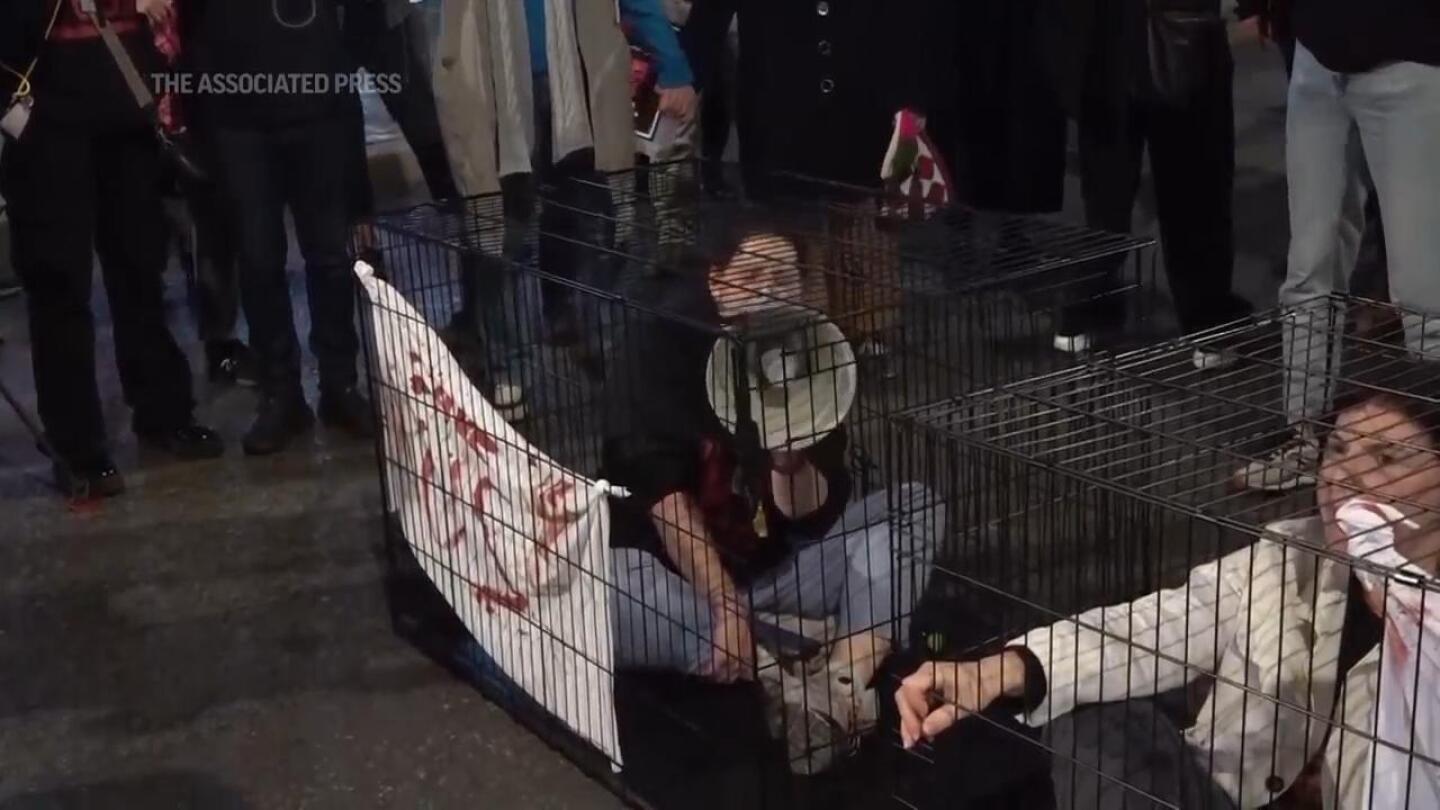 Protesters lock themselves in cages, blocking Tel Aviv road as they demand the release of hostages still held in Gaza. | AP News