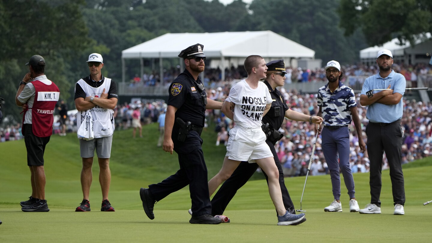 Six protesters run onto 18th green and spray powder, delaying finish of Travelers Championship