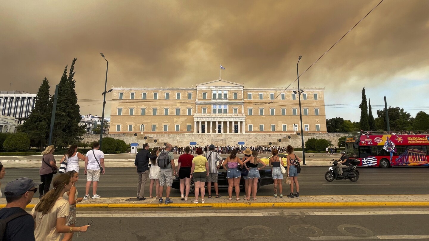 A wildfire near Greece’s capital darkens the skies over Athens and advances fast